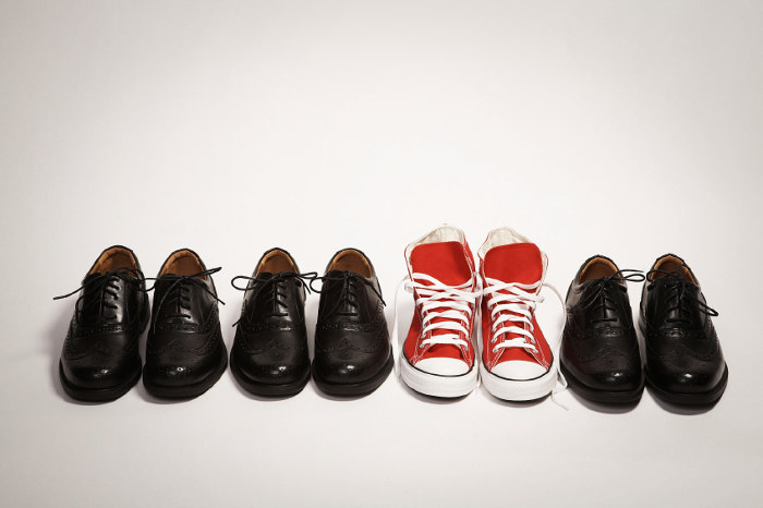 Roter Schuhe zwischen schwarzen Schuhen